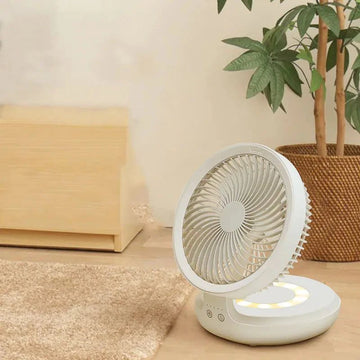 White portable folding desk fan with remote control on a wooden desk